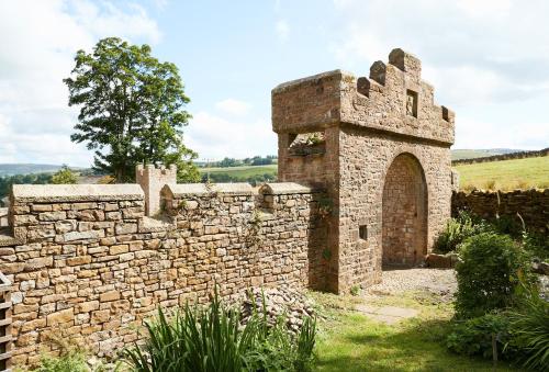 an old stone building with a brick wall at The Old Buttress at Rotherhope Towers in Alston