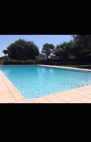 une grande piscine bleue avec des arbres en arrière-plan dans l'établissement Charmant appartement dans un domaine avec piscine, à Mougins