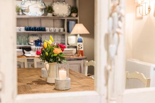 a table with flowers and a candle on it at Chart House 10 Guests in Tenby