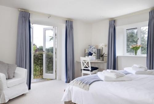 a white bedroom with two beds and a window at Cats Abbey Cottage in Northleach