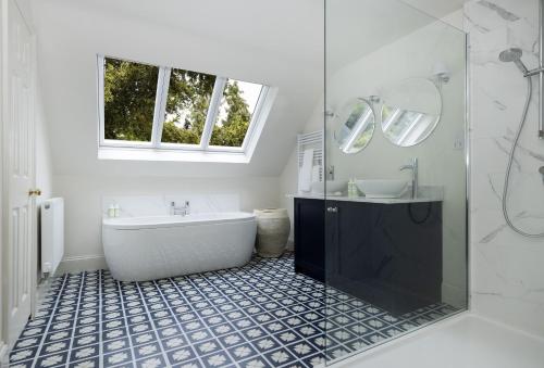 a bathroom with a tub and a sink and a mirror at Cats Abbey Cottage in Northleach