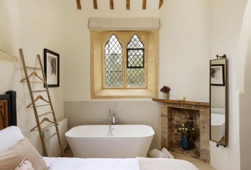 a bathroom with a bath tub and a fireplace at The Old Mission Church in Ebrington