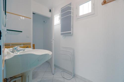 een witte badkamer met een wastafel en een spiegel bij Rêve De Mer - Appartement 6 in Frontignan