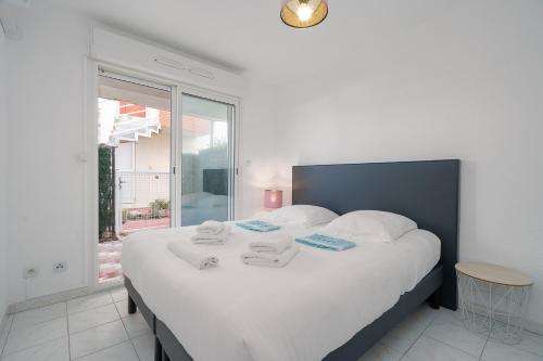 een slaapkamer met een groot wit bed en handdoeken bij Rêve De Mer - Appartement 6 in Frontignan