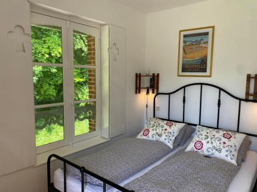 a bedroom with a bed and two windows at La Maison du Cavalier, Chateau de lAvenue in Pierrefitte-en-Auge