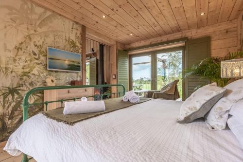 ein Schlafzimmer mit einem großen Bett und einem TV an der Wand in der Unterkunft Olive Tree House in Chalvington