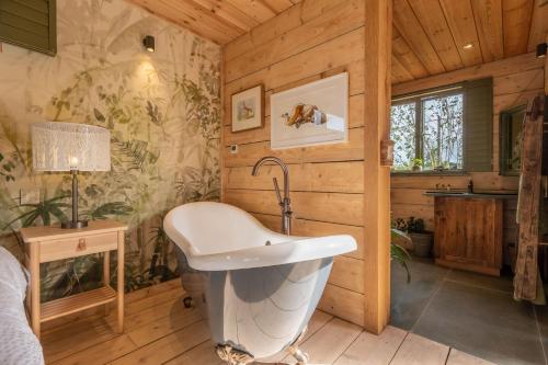 uma casa de banho com banheira num quarto de madeira em Olive Tree House em Chalvington