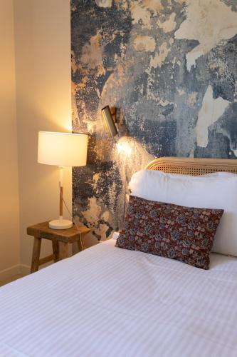 a bedroom with a bed with a lamp and a wall at Villas les Capucines in Sète