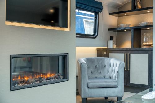 a living room with a fireplace and a chair at JOIVY Elegant houseboat near Canary Wharf in London