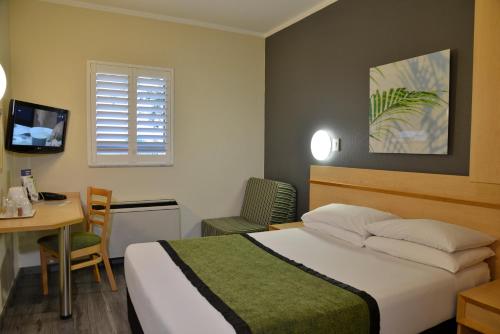 a bedroom with a bed and a table and a desk at Road Lodge Southgate in Southgate