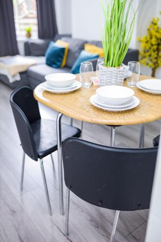 a wooden table with chairs and plates on it in a living room at Beautiful 2 Bedroom House - Free Parking - LT House in Leicester