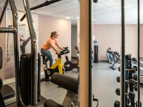 a woman riding a exercise bike in a gym at Hotel Mercure Graz City in Graz