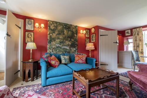 a living room with a blue couch and red walls at Beau Repaire in Coneysthorpe