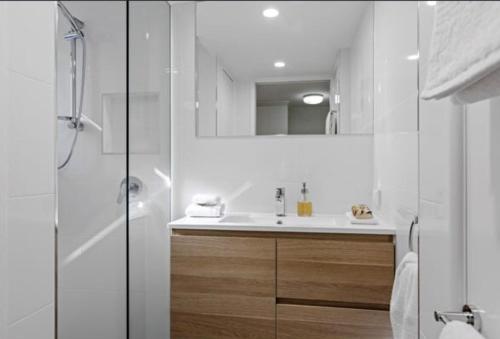 La salle de bains blanche est pourvue d'un lavabo et d'une douche. dans l'établissement Mooloolaba Waterfront Unit - sleeps 8, à Mooloolaba