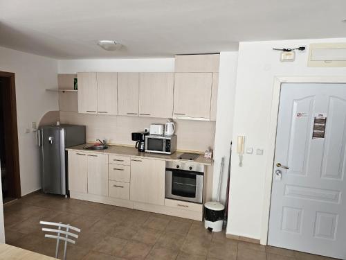a kitchen with white cabinets and a microwave and a refrigerator at Apartment Fort Noks in Sveti Vlas
