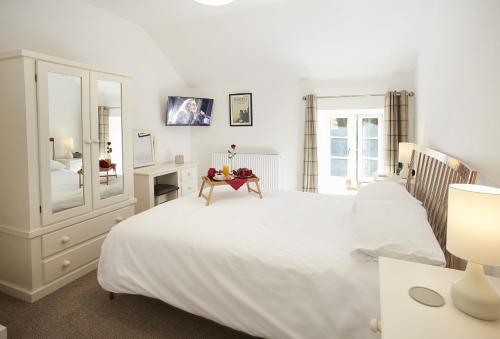 een slaapkamer met een groot wit bed en een spiegel bij Wisteria Cottage Ceredigion in Ystrad Meurig