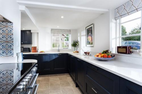 a kitchen with black cabinets and a bowl of fruit on the counter at Wisteria Cottage in Urchfont