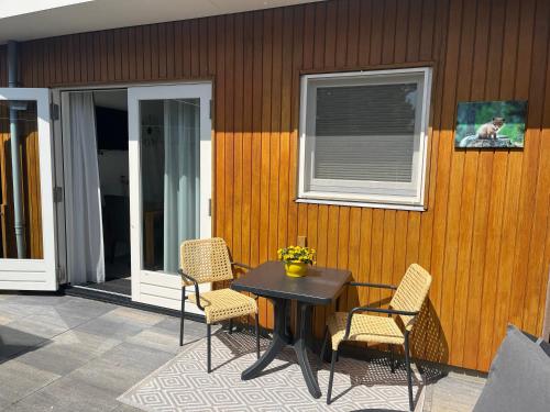 een patio met een tafel en stoelen en een raam bij Luxe kamer Chambre Renard met eigen terras in Zoutelande