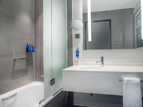 a bathroom with a sink and a shower and a mirror at Radisson Blu Waterfront Hotel, Stockholm in Stockholm