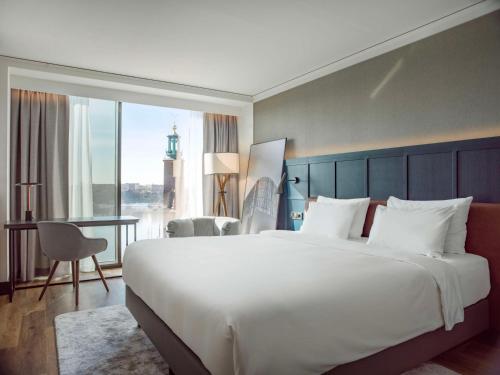 a large white bed in a hotel room with a view at Radisson Blu Waterfront Hotel, Stockholm in Stockholm