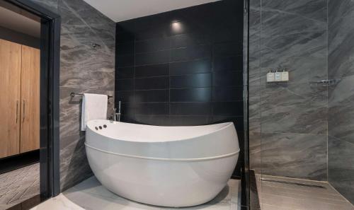 a bathroom with a white tub and a glass shower at Park Inn by Radisson, Lagos Victoria Island in Lagos