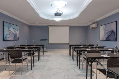 a conference room with tables and a white screen at Park Inn by Radisson, Lagos Victoria Island in Lagos