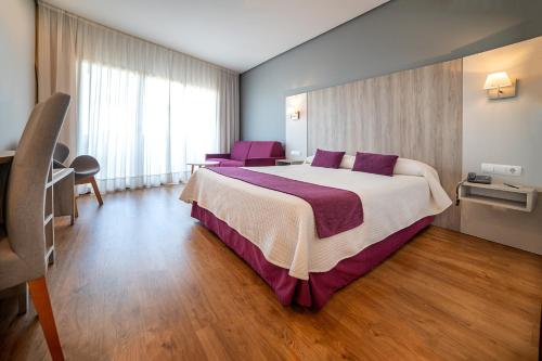 a hotel room with a large bed and purple chairs at Albir Playa Hotel & Spa in Albir