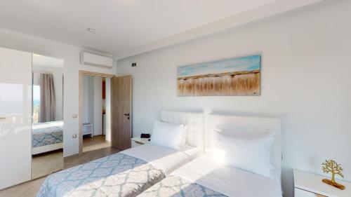 a white bedroom with a bed and a painting on the wall at Golden Lion Parga in Parga