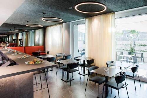 a restaurant with tables and chairs and a large window at Amedia Hotel Milan, Trademark Collection by Wyndham in Milan
