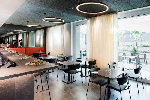 a restaurant with tables and chairs and a large window at Amedia Milano, Trademark Collection by Wyndham in Milan