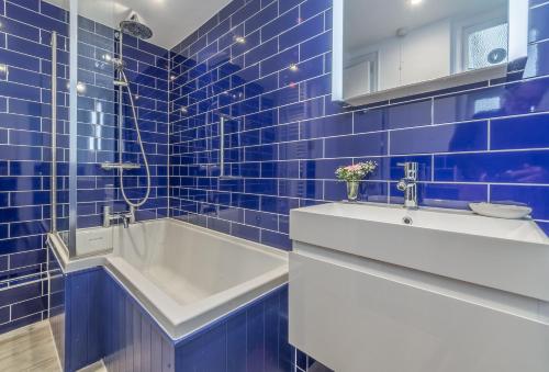 Khina Cottage في Kingsgate: حمام من البلاط الأزرق مع حوض استحمام ومغسلة