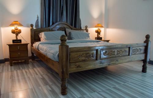 a bedroom with a large wooden bed with two lamps at Klai house 
