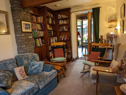 a living room with a couch and chairs and bookshelves at Bryn Elltyd Eco House in Blaenau-Ffestiniog