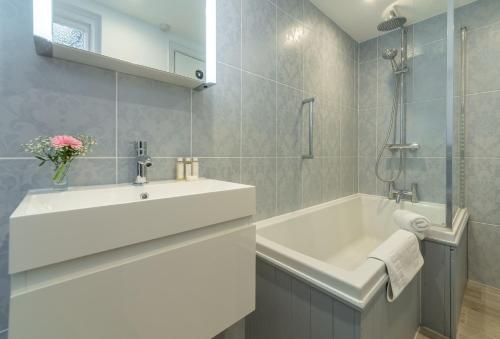 a bathroom with a white sink and a bath tub at Lodesman Cottage in Kingsgate