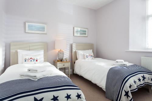 two beds in a room with white and blue stripes at Solebay Cottage in Lower Boscaswell