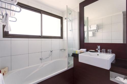 努美阿的住宿－Ramada Hotel & Suites by Wyndham Noumea，带浴缸、水槽和窗户的浴室