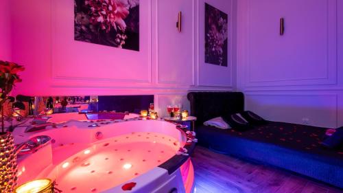 a pink room with a tub and a couch at Vistula Boulevards Jacuzzi Apartment in Kraków