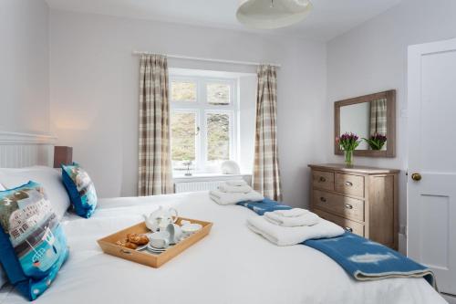 a white bed with a tray with a teddy bear on it at Verity Cottage in Saint Merryn