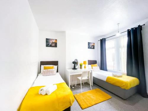 um quarto com 2 camas, uma secretária e uma janela em Sapphire Apartment Leicester em Leicester