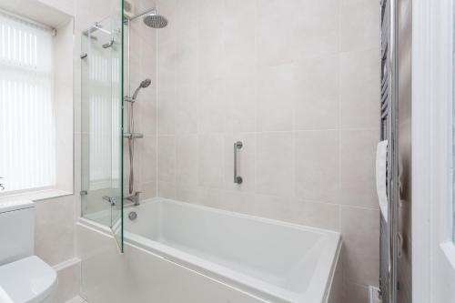 a white bathroom with a tub and a toilet at Verity Cottage in Saint Merryn