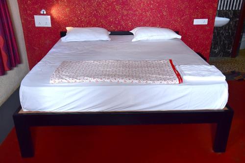 a bed in a room with a red wall at Paradise Quest Nature Farmhouse in Kālapettai