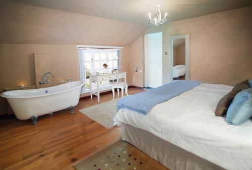 a bedroom with a bed and a tub and a sink at Spring Water Barn in Helston
