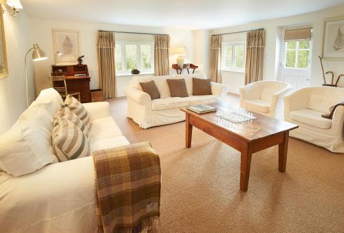 Elle comprend un salon doté d'un mobilier blanc et d'une table basse. dans l'établissement Woodland Cottage Devon, à Romansleigh