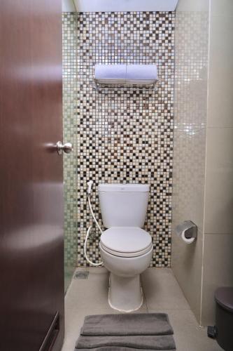 a bathroom with a toilet and a tile wall at @Hom Semarang Simpang Lima in Semarang