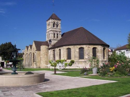 a large church with a clock tower in a park at Ô Cottage in Deuil-la-Barre