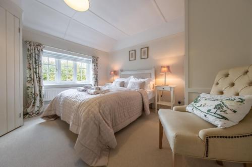 a bedroom with two beds and a chair at Densford Cottage in Amberley