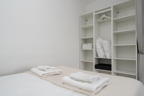 een witte slaapkamer met witte handdoeken op een bed bij Sunny Studio W/ Balcony in Portimão by LovelyStay in Portimão