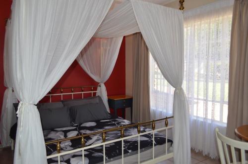 a bedroom with a canopy bed with white curtains at Holiday Flat Stormvoel 547 in Hazyview