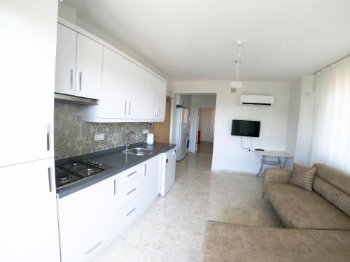a kitchen and living room with white cabinets and a couch at Doğa Apart in Ortaca