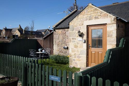 a house with a green fence and a wooden door at Avocet Cottage in Lucker